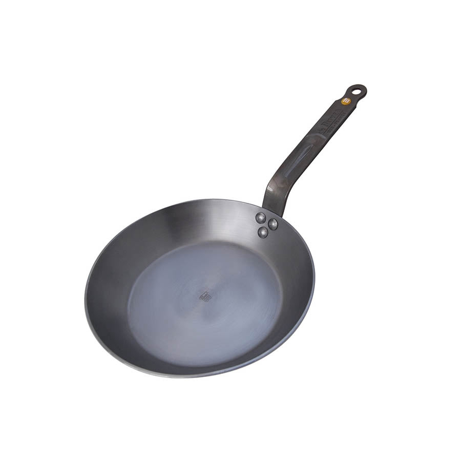 A black carbon steel frying pan with a riveted iron handle.